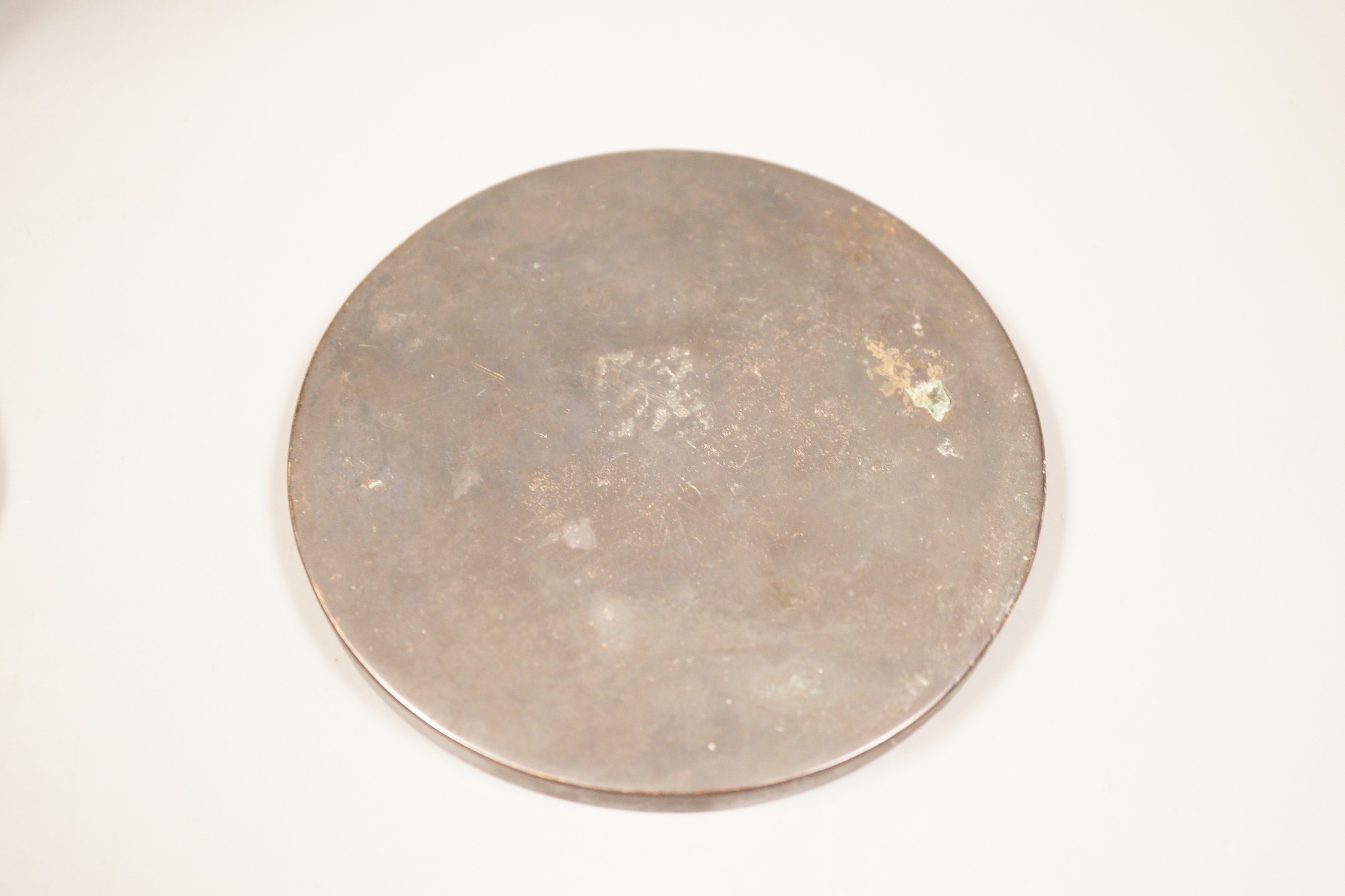 A Chinese bronze mirror, 11cm diameter, a jadeite floral carving on stand with a metal relief plaque, and a pair of bracelets